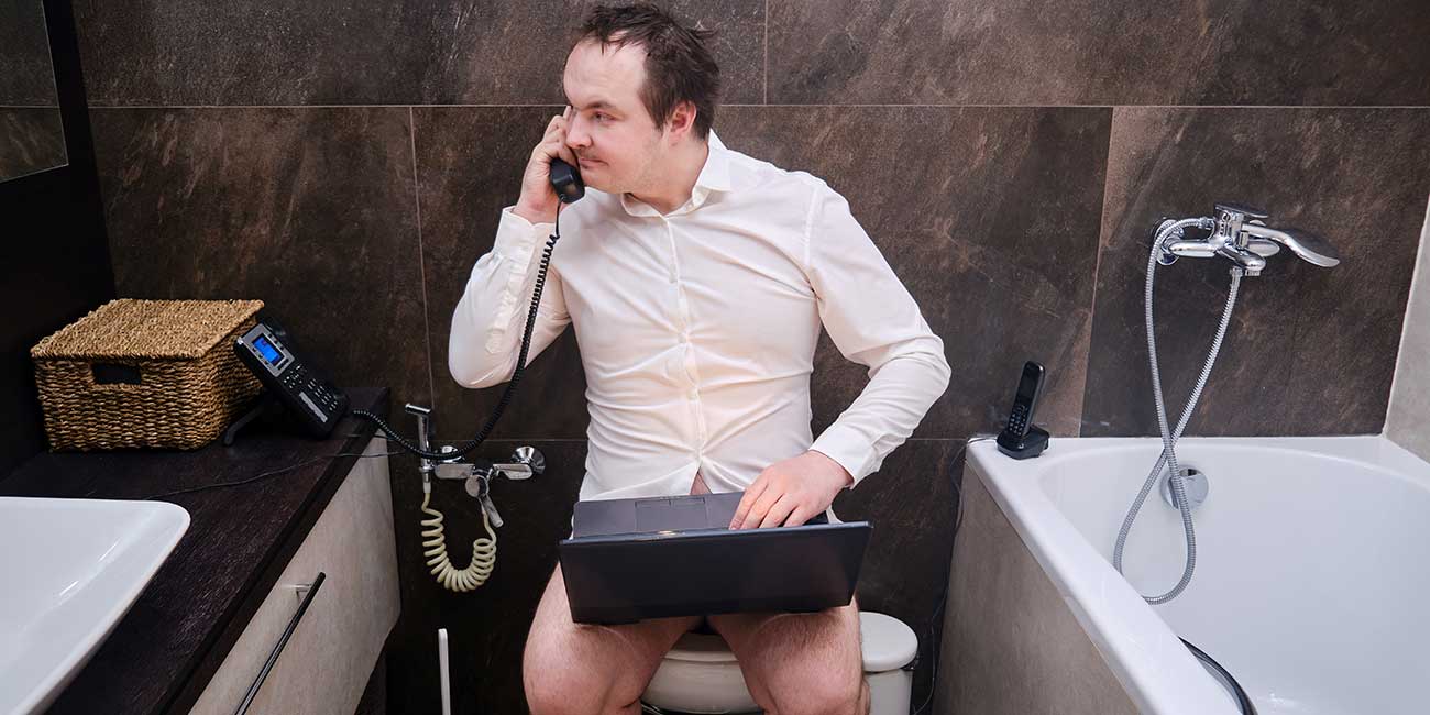 Business-Mann telefoniert am Digital Workplace auf der Toilette mit VoIP-Telefonanlage von yuutel