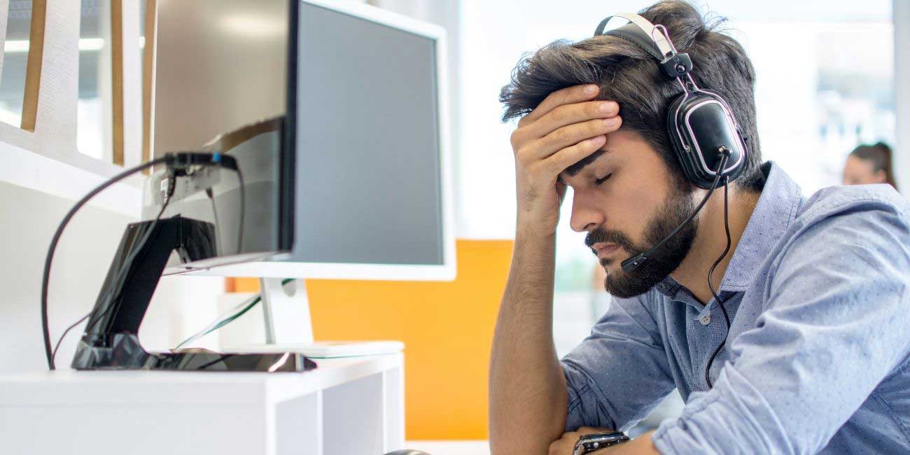 Callcenter-Mitarbeiter mit Headset verzweifelt vor Computer und braucht Krisentipps für Callcenter von yuutel