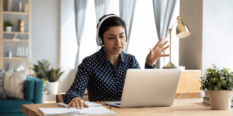 Frau telefoniert über VoIP-Lösung von yuutel mit Headset vor Laptop im Homeoffice
